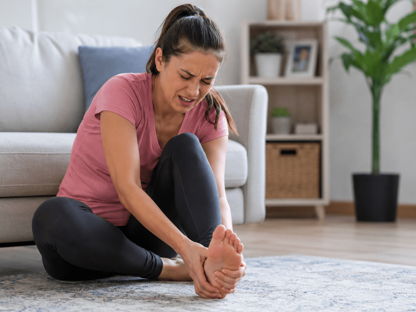 Woman holding her foot due to plantar fasciitis pain